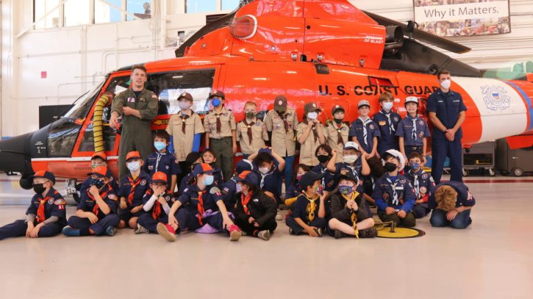 Pack 88 cub scouts seated in front of a Coast Guard helicopter