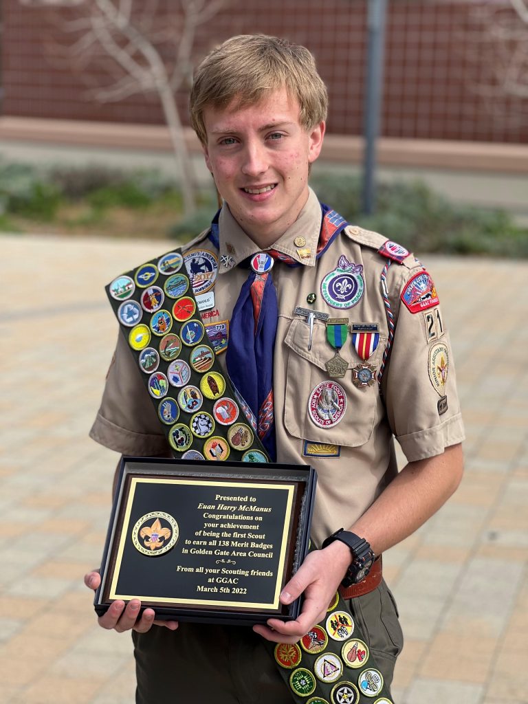 Scout holding a plaque recognizing his accomplishment of earning all 138 merit badges.